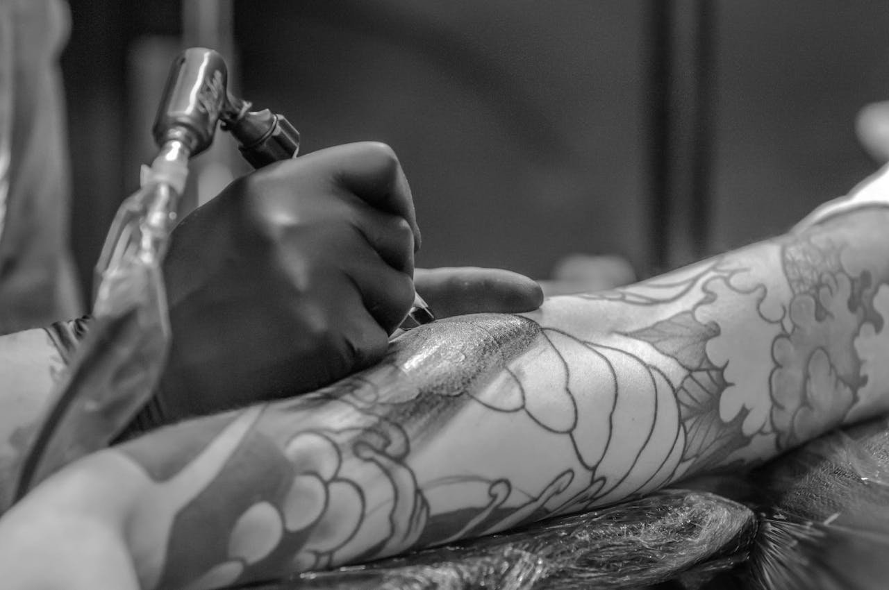 About Grayscale Photo Of Person Applying Tattoo 955938